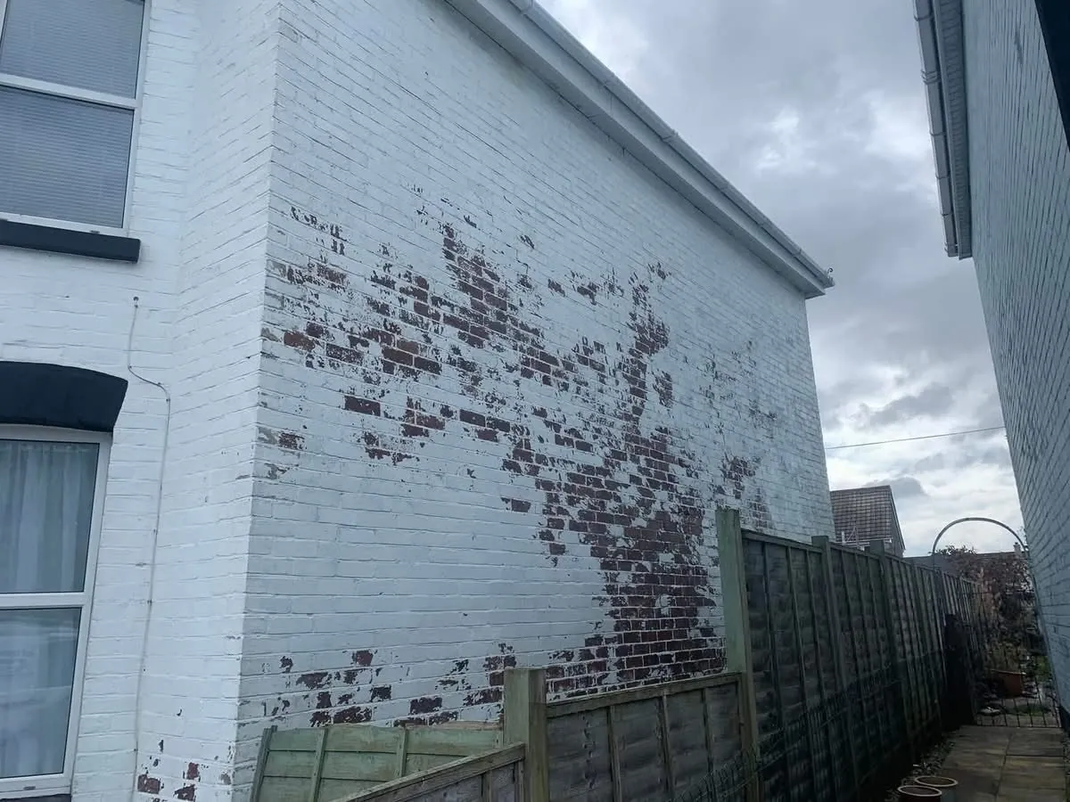 Peeling paint on a brick wall before redecoration in Seaton